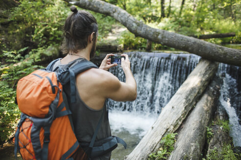 Junger Mann nimmt ein Handy-Foto an einem Wasserfall im Wald - VPIF00030