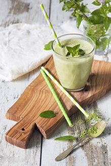 Glass of green smoothie with coconut milk, banana, matcha powder garnished with mint leaves - YFF00677