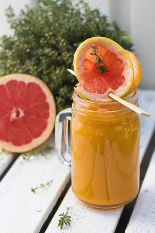 Glass of fruit smoothie with Pink Grapefruit, orange, mango and thyme stock photo