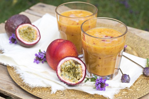 Zwei Gläser Fruchtsmoothie mit Passionsfrucht, Nektarine, Granatapfelsaft und Reismilch, lizenzfreies Stockfoto