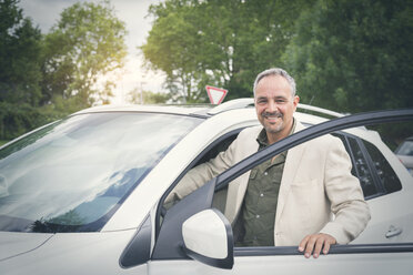 Porträt eines lächelnden reifen Geschäftsmannes, der in sein Auto steigt - JUNF00885