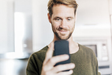 Portrait of smiling man looking at cell phone - GIOF03172