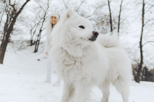 Weißer Hund im Schnee mit lächelnden Besitzer beobachten aus dem Hintergrund - ZEDF00823