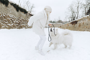 Junge Frau spielt mit ihrem Hund im Schnee - ZEDF00828