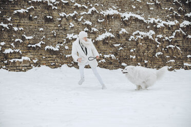 Junge Frau spielt mit ihrem Hund im Schnee - ZEDF00830