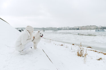 Serbien, Petrovaradin, weiß gekleidete junge Frau mit weißem Hund am Flussufer - ZEDF00834