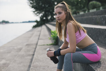 Sportliche Frau macht eine Pause am Flussufer - MOMF00228