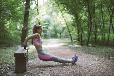 Junge Frau beim Sport auf einer Bank im Wald - MOMF00234