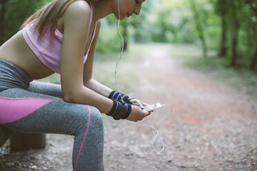 Sporty woman having a break in forest - MOMF00236