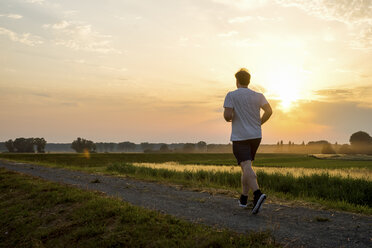 Mann läuft in ländlicher Landschaft bei Sonnenuntergang - PUF00690