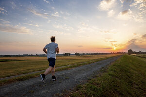 Mann läuft in ländlicher Landschaft bei Sonnenuntergang - PUF00691