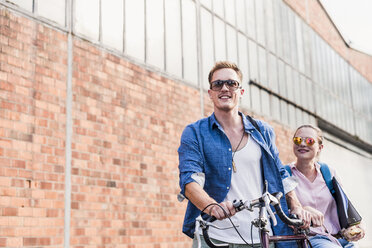 Junges Paar mit Fahrrad und Sonnenbrille unterwegs - UUF11518
