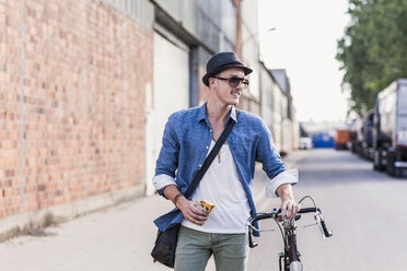 Junger Mann mit Fahrrad auf der Straße - UUF11522