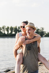 Junger Mann nimmt seine Freundin am Flussufer Huckepack - UUF11535