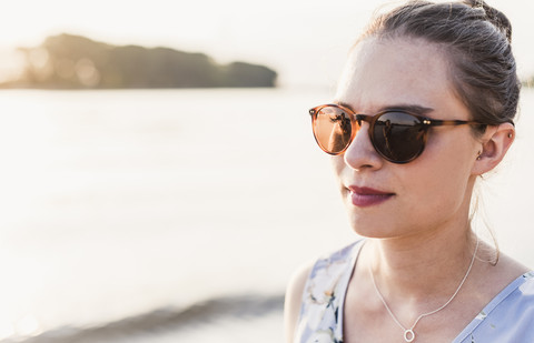 Junge Frau mit Sonnenbrille am Flussufer, lizenzfreies Stockfoto