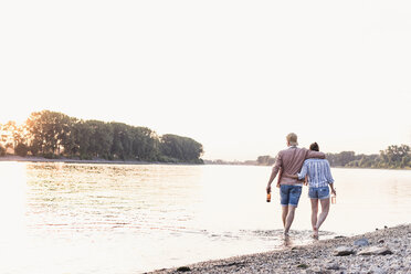 Young couple wading in river at sunset - UUF11556