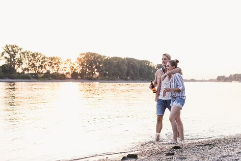 Young couple wading in river at sunset - UUF11557