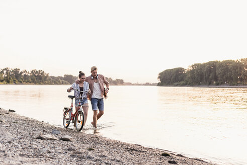 Young couple with bicycle wading in river - UUF11558