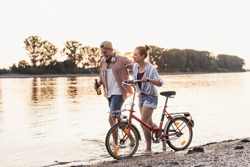 Young couple with bicycle wading in river - UUF11559