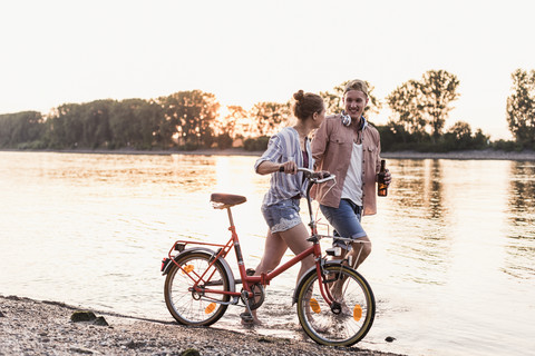 Junges Paar mit Fahrrad watet im Fluss, lizenzfreies Stockfoto