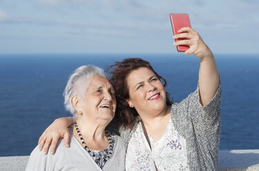 Großmutter und Enkelin machen ein Selfie vor dem Meer - RAEF01933