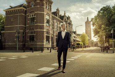 Netherlands, Venlo, businessman walking on a street with plastic bag over his head - KNSF02405