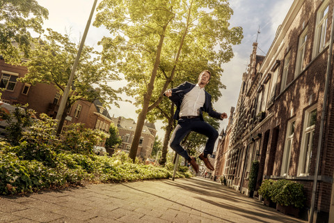 Niederlande, Venlo, Geschäftsmann springt auf Bürgersteig, lizenzfreies Stockfoto