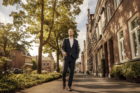Niederlande, Venlo, selbstbewusster Geschäftsmann auf dem Bürgersteig, lizenzfreies Stockfoto