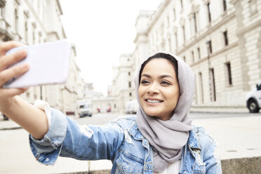 UK, England, London, junge Frau mit Hidschab, die ein Selfie in der Stadt macht - IGGF00122