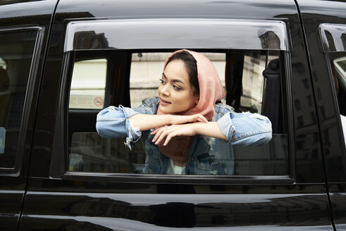UK, England, London, junge Frau mit Hidschab, die aus einem Taxi schaut - IGGF00132