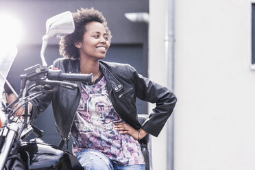 Smiling young woman with her motorcycle - UUF11564