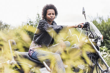 Porträt einer jungen Frau mit ihrem Motorrad - UUF11566
