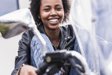 Porträt einer lächelnden jungen Frau mit ihrem Motorrad - UUF11567