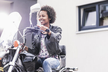 Smiling young woman on her motorcycle - UUF11568