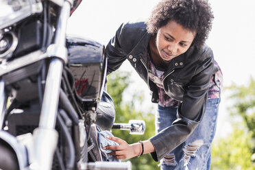 Junge Frau putzt ihr Motorrad - UUF11570