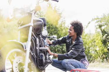 Young woman cleaning her motorcycle - UUF11571