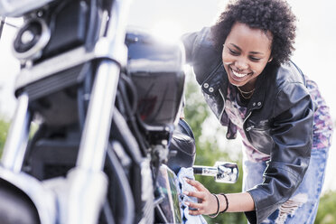 Junge Frau putzt ihr Motorrad - UUF11575