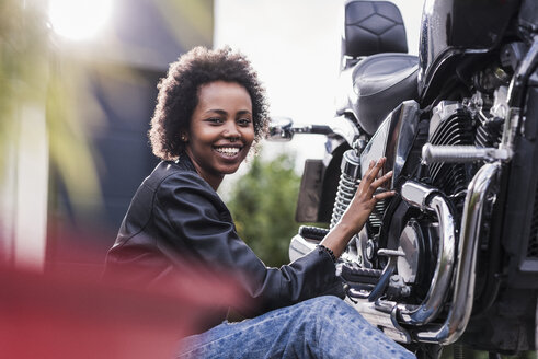 Junge Frau, die ihr Motorrad wartet - UUF11577