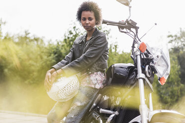 Porträt einer jungen Frau mit ihrem Motorrad - UUF11579