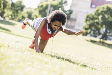 Young woman exercising on meadow in park - UUF11596