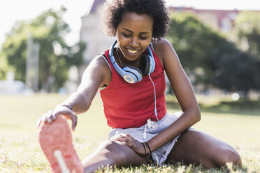 Young woman stretching on meadow in park - UUF11597