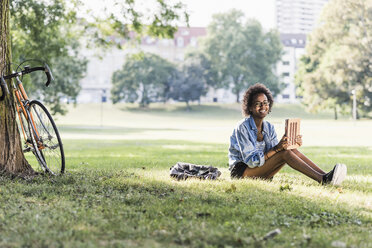 Smiling young woman resting in park with tablet - UUF11613