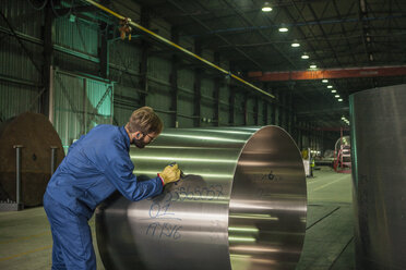 Arbeiter, der in einer Fabrik Metall beschriftet - ZEF14518