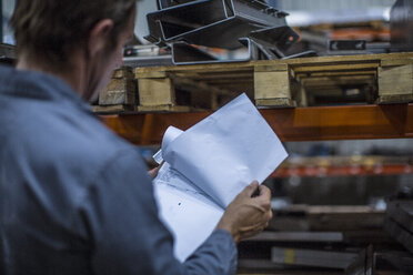 Worker standing with clipboard in warehouse - ZEF14533