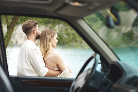 Young couple outside car looking at view stock photo