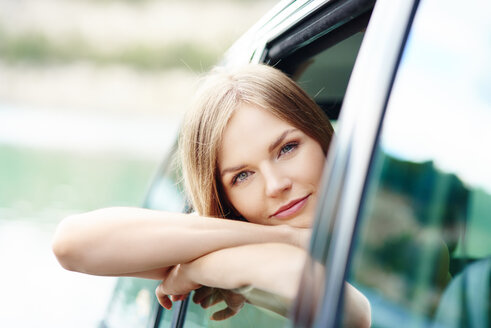 Porträt einer jungen Frau, die sich aus dem Autofenster lehnt - ABIF00021
