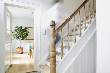 Mann, der auf einer Holztreppe in einem alten Landhaus nach oben geht - PDF01266