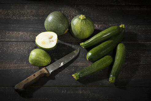 Acht Kugelkürbisse und Zucchini auf dunklem Holz - MAEF12397