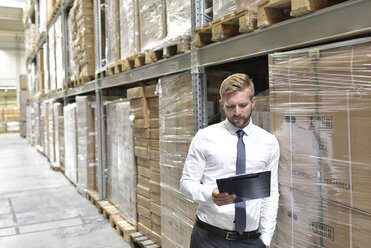 Businessman looking at clipboard in warehouse - LYF00771