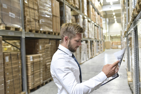 Businessman looking at documents in warehouse stock photo